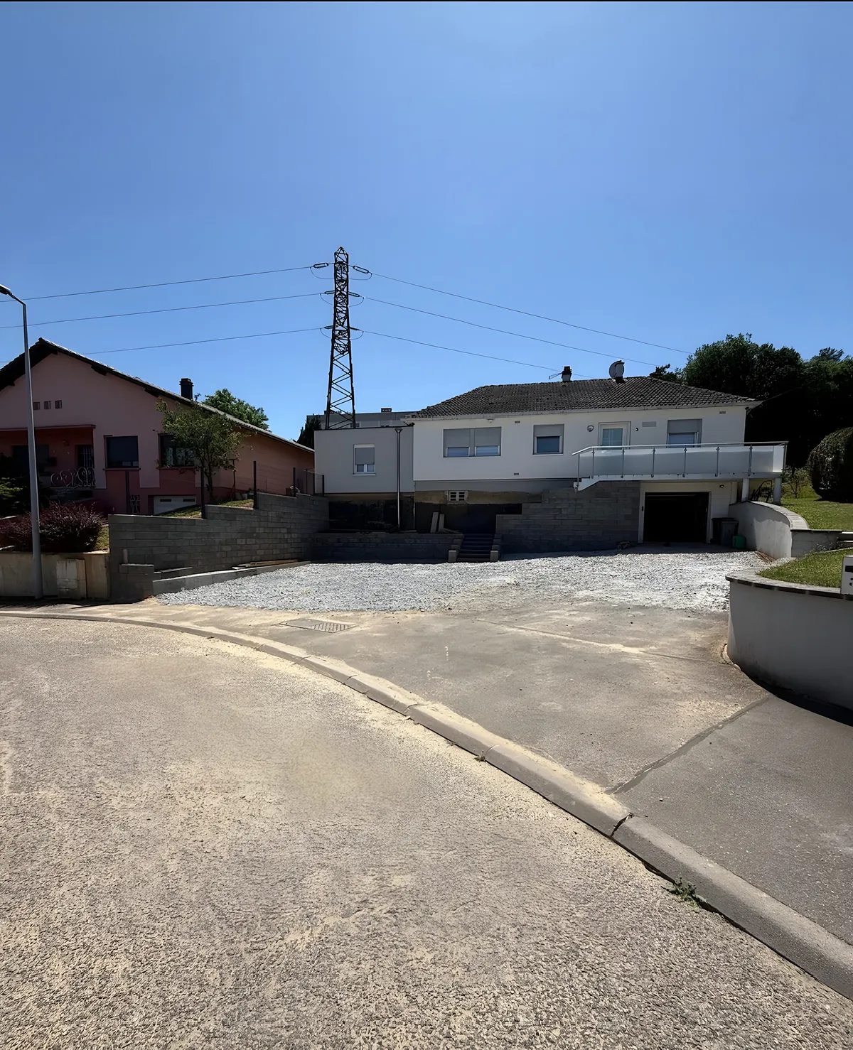 Murs de soutènement en blocs béton créés devant une maison, avec escalier central et accès gravillonné