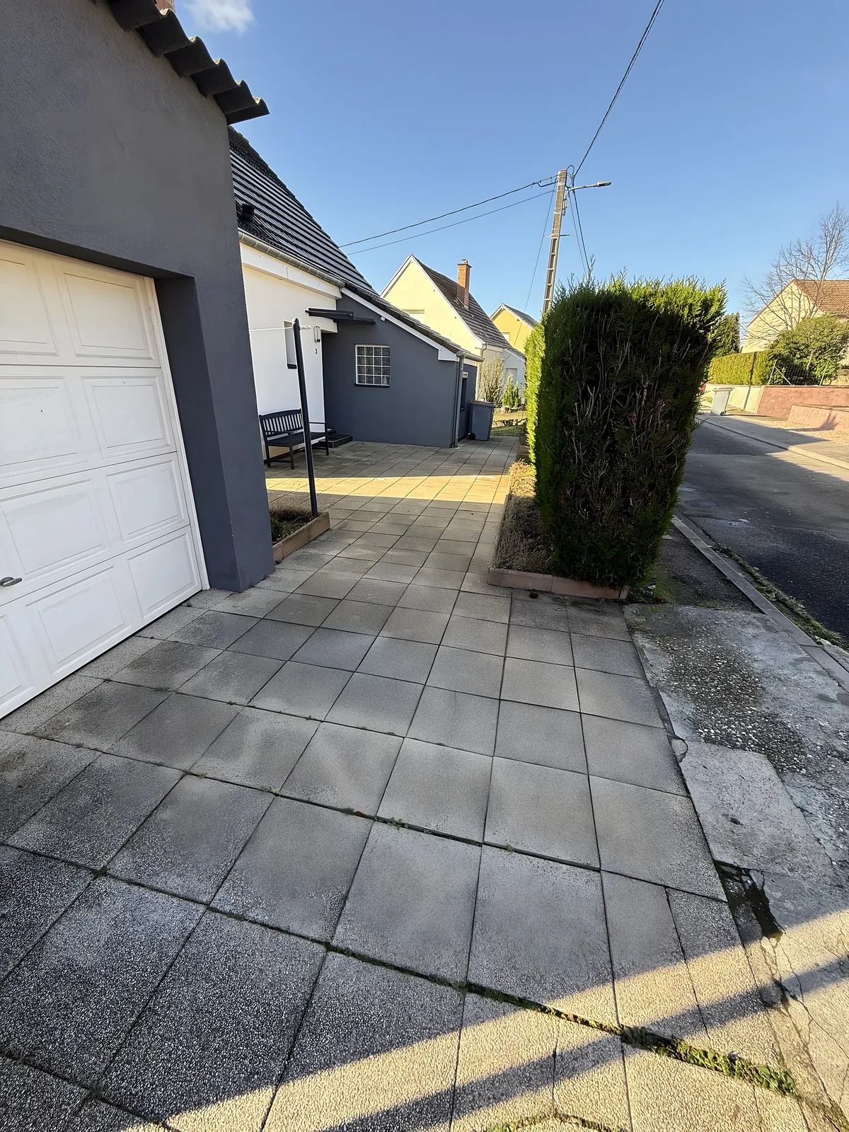 Ancienne cour en dalles béton usées devant un garage, avant réfection